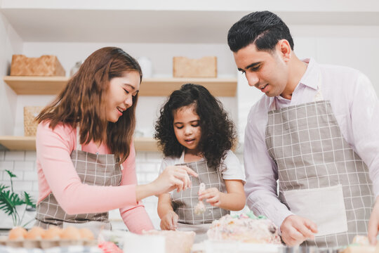 Happy Family Group Of Three Diverse Family, Asian And Middle Eastern Preschool African Arab Kid Person Make Cake Cooking In Kitchen, Father Mother Prepare Decoration Pretty With Fun Educate.