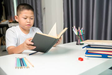 Boy person sitting study indoor at home, Male kid student online learning and doing homework on desk, young child reading and writing a book on table. concept of education, technology cyberspace