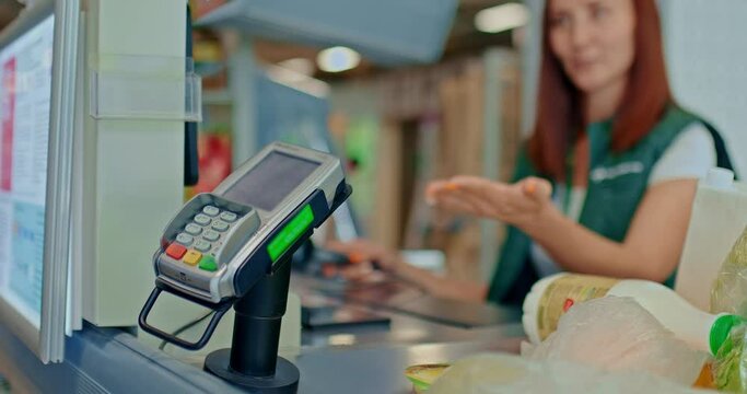 Cashier offers to pay for purchases with a bank card at the supermarket. Woman's hand puts a bank card to the contactless payment terminal. 4k, ProRes