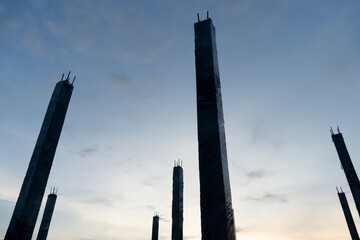 Silhouette of cement columns surrounded by plastic wrap during the curing process. under the evening sky.