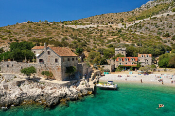 View on Dubovice Beach on the island of Hvar, Croatia with moored boats and many swimmers. Church...