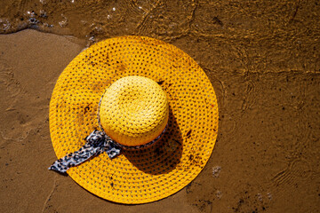 Fototapeta na wymiar Żółty kapelusz na plaży, wakacje, piękny słoneczny dzień na plaży, morze, piasek. 