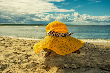 Żółty kapelusz na plaży, wakacje, piękny słoneczny dzień na plaży, morze, piasek. 