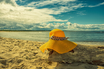 Żółty kapelusz na plaży, wakacje, piękny słoneczny dzień na plaży, morze, piasek.  - obrazy, fototapety, plakaty