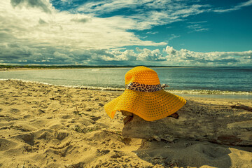 Żółty kapelusz na plaży, wakacje, piękny słoneczny dzień na plaży, morze, piasek.  - obrazy, fototapety, plakaty