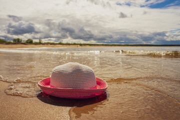 Kapelusz leży na brzegu plaży. Linia brzegowa, morze Bałtyckie w piękny słoneczny dzień. 