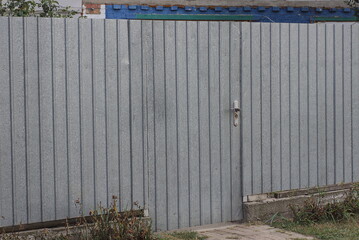 gray long metal fence wall and closed door in the rural street
