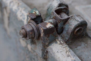 part of a gray metal old structure with fasteners and plates with a brown rusty bolt on the street