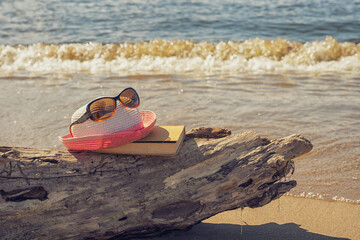 Akcesoria plażowe ułożone na kawałku drewna wyrzuconego na brzeg, wakacje, słoneczny plażowy dzień, morze, piasek. 