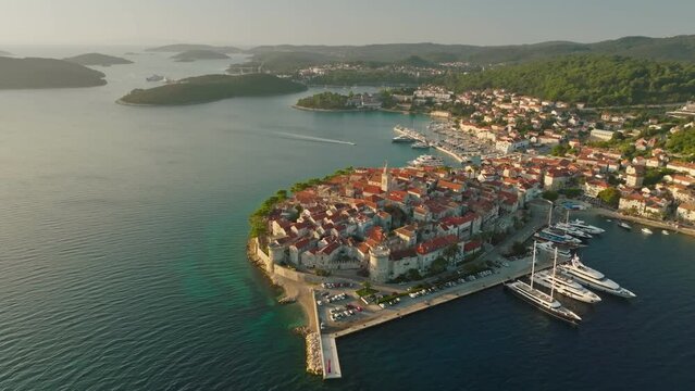 Flying over medieval mediterranean Croatian town of Korcula in morning sun lights. Gorgeous old town on the green island of Korcula, Croatia - birthplace of Marco Polo