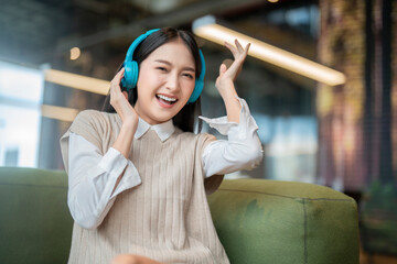 relax joyful casual asian female adult woman casual cloth enjoy listening music from streaming online playing music playlist application on smartphone via earphone on sofa couch at co working space  