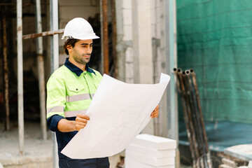 Construction worker in hardhat and vest with blueprint on construction site