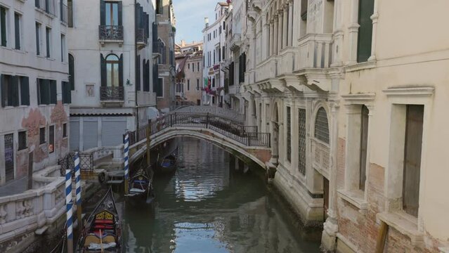 Canal, bridges and old historical buildings of Venice early in the morning, without people. Camera moves along the bridge over canal, gimbal shot. Venice, Italy