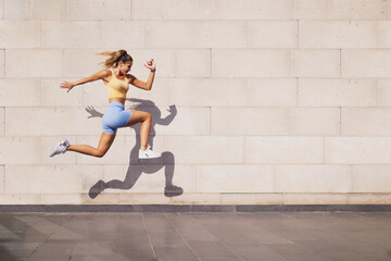 Jumped woman with a shadow on a wall background.