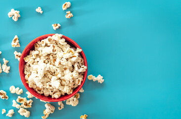 Plate with popcorn on a blue background, flat lay.