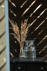 A bouquet of dried pampas grass flowers in a glass vase on a dark table. An element of decor and interior decoration.