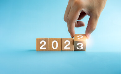 The calendar year 2022 changed to 2023, success concept. Wooden cube blocks turning by hand for the...