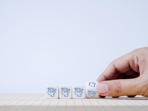 The human head symbol changing, flipping to AI or artificial intelligence icon on white cube blocks in hand for technological development and transform for business and lifestyle for the future.