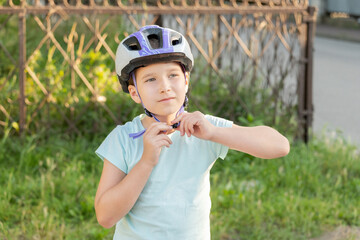 School age biker girl putting on or taking off, fastening her protective biking helmet, portrait, face closeup, copy space. Children, kids biking, cycling safety and protection from injuries. Sports