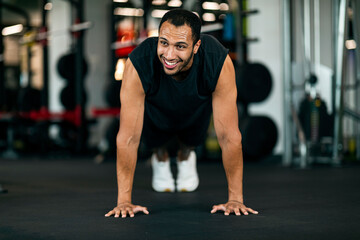 Fototapeta na wymiar Sporty Black Male Making Straight Arm Plank Exercise While Training At Gym