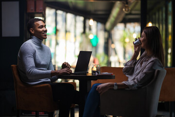 Friends at a cafe after work. Business colleagues working on laptop and drinking coffee in a restaurant..