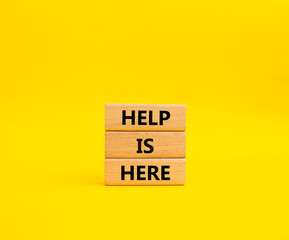 Help is here symbol. Wooden blocks with words Help is here. Beautiful yellow background. Business and Help is here concept. Copy space.