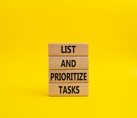 List and prioritize tasks symbol. Concept words List and prioritize tasks on wooden blocks. Beautiful yellow background. Business and List and prioritize tasks concept. Copy space.