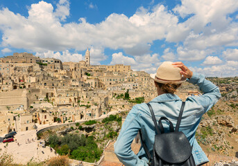tourist girl with hat  looking the stunning view of the Sassi di Matera in Italy on a warm summer...