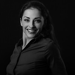 Beautiful thinking toothy smiling business woman looking in blue shirt on black background with empty copy space for text. Closeup