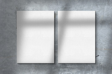 Two empty white vertical rectangle poster or business card mockups with diagonal window shadow on the gray concrete wall.Flat lay  top view. For advertising  brand design  stationery presentation