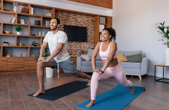 Glad young african american couple athletes in sportswear do exercises or practicing yoga