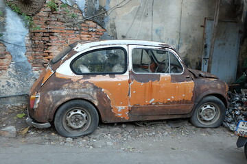 An old, rusty orange antique car that has been abandoned at Talat Noi, one of the oldest districts in Bangkok.