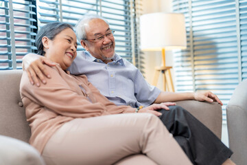 Senior couple sitting on the sofa at home watching television and relaxation together. Enjoyment to spend time together with smile and happy. Modern elderly lifestyle and retirement concept