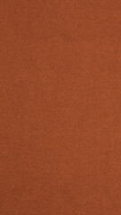 Bright brown colored paper texture. Dark orange vertical background. Mobile phone wallpaper. Textured surface, fibers and irregularities are visible. Top-down