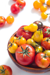 Bowl with freshly picked from the garden tomatoes on a white background. Red and yellow organic tomatoes. Harvest time. Healthy eating concept.