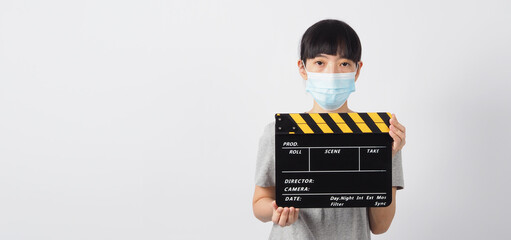 Asian woman wear face mask and hand's holding black clapper board or movie slate or clapboard use...