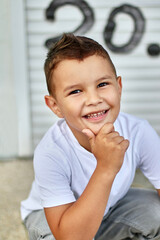 A handsome little boy is posing for the camera, smiling. Carefree childhood.