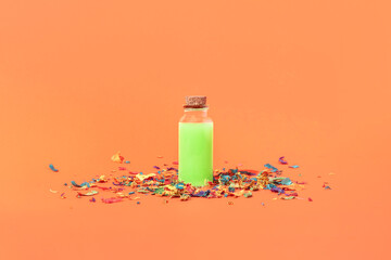 Fototapeta premium Minimal Halloween concept with a neon green magic potion bottle and colorful confetti on orange background. Creepy, spooky holiday aesthetic. Party idea.