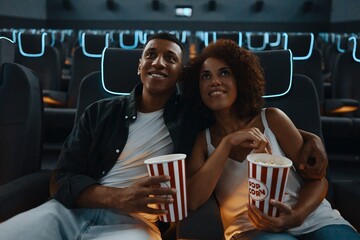 A couple in love, friends watching a movie with popcorn in the cinema.