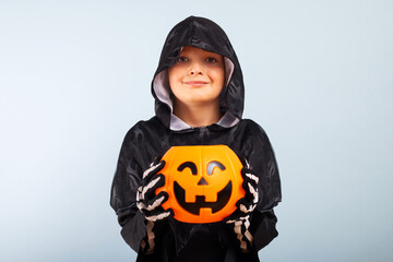 Happy Halloween! Cute little boy in a costume with a pumpkin basket jack-o-lantern