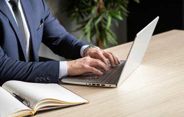 young businessman in a dark blue suit working in the office, typing on computer