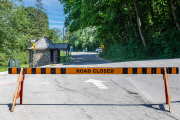 Road closed barricade on a narrow road through a park on a summer's day.
