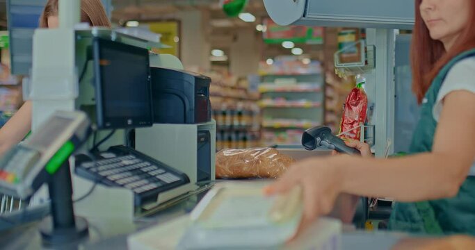 Female cashier punches goods with a scanner at the supermarket checkout. Purchase of products in the store. Cashier works as a scanner, fixes the goods in the receipt. 4k, ProRes