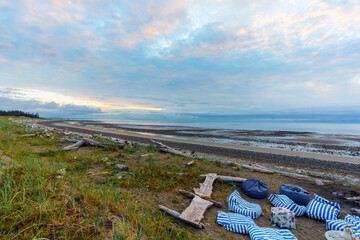 Campfire cushions and makeshift wooden seating on natural BC beach at dawn.