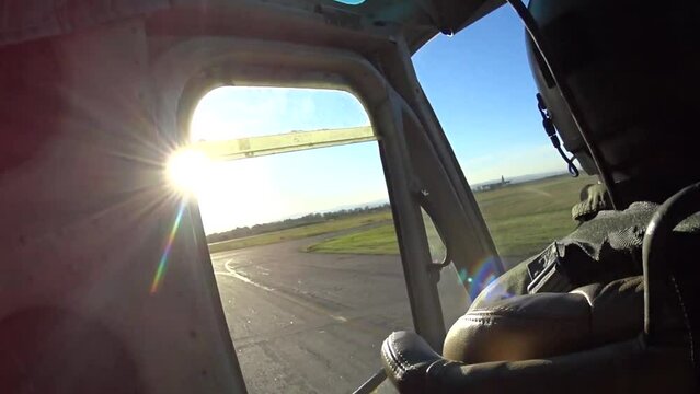 vista desde la ventanilla de un helicoptero de transporte militar, se observa un avion de transporte de carga carretando por la pista de aterrizaje, vista desde la espalda del piloto con luz ocaso