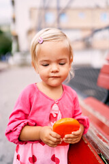 Little girl with a toy in her hands leans on a bench. Portrait. High quality photo