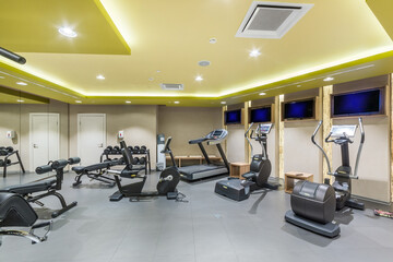 Fototapeta na wymiar The interior of a modern gym with treadmills, exercise bikes and dumbbells for power loads.