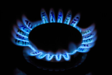 Burning gas burner on a household stove with flames in the form of euro banknotes