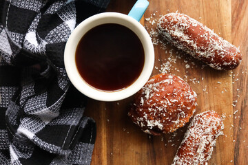 cup of coffee with Koesisters and coconut covered doughnuts. Traditional South African sweet snack usually eaten on a Sunday morning. 