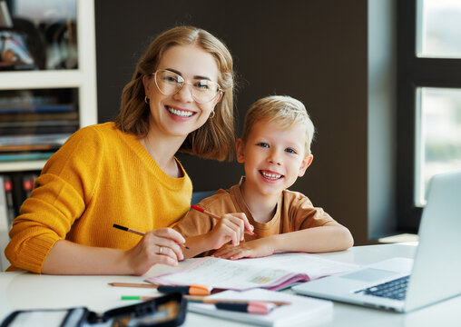 Cheerful mother doing homework with son at home